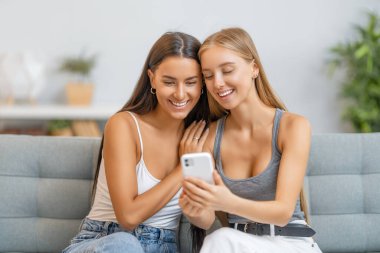 Genç kadınlar telefon kullanıyor. Komik kızlar evde eğleniyor..