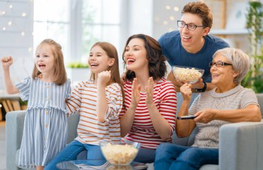 Mutlu aile projektörü, TV, akşam evde patlamış mısırlı filmler. Büyükanne, anne, baba ve kızlar birlikte vakit geçiriyorlar..