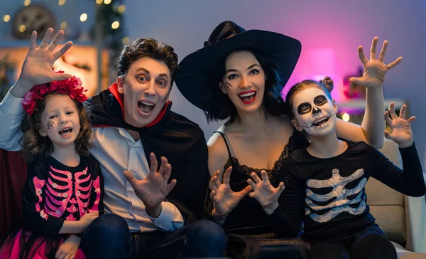 Anne, baba ve çocukları evde eğleniyorlar. Cadılar Bayramı 'nı kutlayan mutlu aile. İnsanlar karnaval kostümü ve makyaj yapıyor..