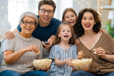 Mutlu aile projektörü, televizyon, evde patlamış mısırlı filmler. Büyükanne, anne, baba ve kızlar birlikte vakit geçiriyorlar..