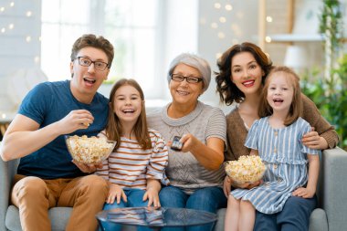 Mutlu aile projektörü, televizyon, evde patlamış mısırlı filmler. Büyükanne, anne, baba ve kızlar birlikte vakit geçiriyorlar..