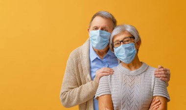 Coronavirus ve grip salgını sırasında yüz maskesi takan yaşlı çift. Virüs ve hastalık koruması, ev karantinası. COVID-2019. Maske takıyor.