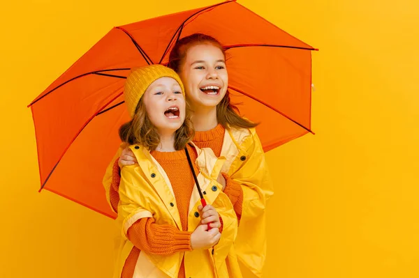 Šťastné Emocionální Děti Smějí Objímají Děti Oranžovým Deštníkem Žlutém Pozadí — Stock fotografie