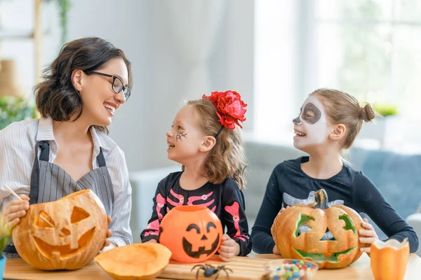 Mutlu aile Cadılar Bayramı için hazırlanıyor. Karnavaldaki anne ve çocuklar evde kostüm giymişler..