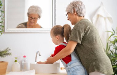 Küçük tatlı bir kız ve büyükannesi ellerini yıkıyorlar. Enfeksiyon ve virüslere karşı koruma.  