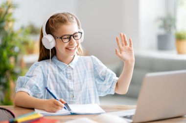 Okula dönelim. Mutlu çocuk masada oturuyor. Ödev yapan ya da online eğitim alan kız.