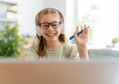 Okula dönelim. Mutlu çocuk masada oturuyor. Ödev yapan ya da online eğitim alan kız.