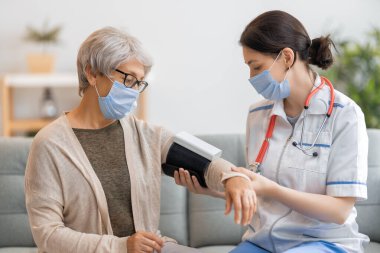 Yaşlı hasta ve doktor kan basıncını ölçüyor.