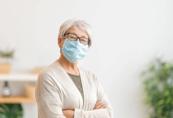 コロナウイルスやインフルエンザの流行中にフェメマスクを着用シニア女性 ウイルスや病気の保護 家庭の隔離 Covid 2019 マスクの着脱 — ストック写真