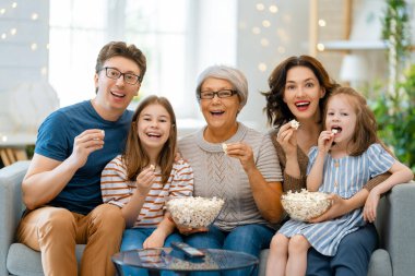 Mutlu aile projektörü, televizyon, evde patlamış mısırlı filmler. Büyükanne, anne, baba ve kızlar birlikte vakit geçiriyorlar..