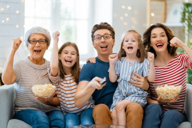 Mutlu aile projektörü, televizyon, evde patlamış mısırlı filmler. Büyükanne, anne, baba ve kızlar birlikte vakit geçiriyorlar..