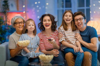 Mutlu aile projektörü, TV, akşam evde patlamış mısırlı filmler. Büyükanne, anne, baba ve kızlar birlikte vakit geçiriyorlar..