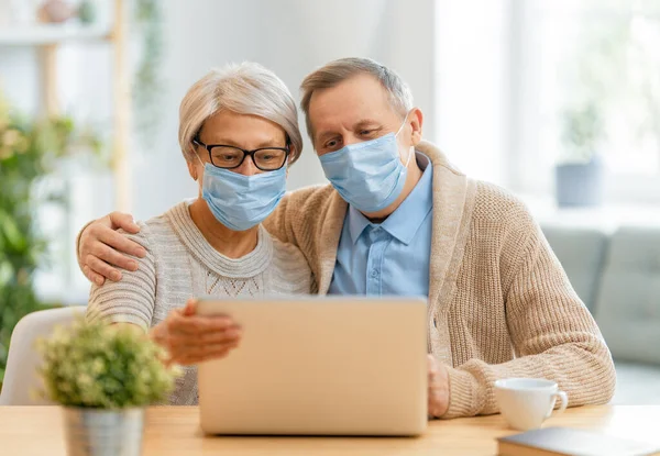 高齢のカップルは顔マスクを着用し コロナウイルスやインフルエンザの発生中にPcを使用しています ウイルスや病気の保護 家庭の隔離 Covid 2019 マスクの着脱 — ストック写真