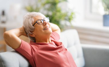 Evdeki odada kanepede oturan son sınıf öğrencisi kadın..