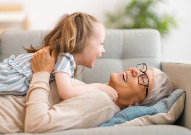 Hoş bir kız ve büyükannesi güneşli bir sabahın tadını çıkarıyorlar. Evde iyi vakit geçir.. 