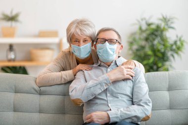 Coronavirus ve grip salgını sırasında maske takan yaşlı bir çift. Virüs ve hastalık koruması, ev karantinası. COVID-2019. Maskeleri çıkarmak ya da çıkarmak.