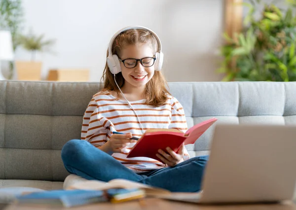 回学校去快乐的孩子正坐在沙发上 做家庭作业或网上教育的女孩 — 图库照片