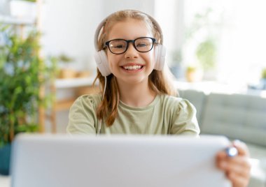 Okula dönelim. Mutlu çocuk masada oturuyor. Ödev yapan ya da online eğitim alan kız.