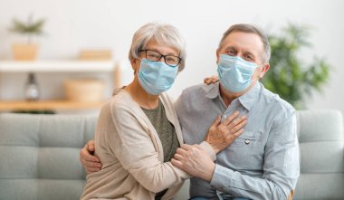 Coronavirus ve grip salgını sırasında maske takan yaşlı bir çift. Virüs ve hastalık koruması, ev karantinası. COVID-2019. Maskeleri çıkarmak ya da çıkarmak.
