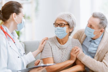 Doktor ve yaşlı çift koronavirüs ve grip salgını sırasında maske takıyor. Virüs koruması, ev karantinası. COVID-2019. Maske takıyor.