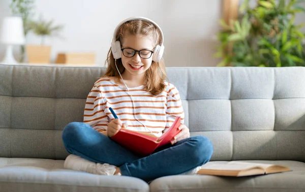 学校に戻る 幸せな子供はソファに座っている 宿題やオンライン教育をする女の子 — ストック写真