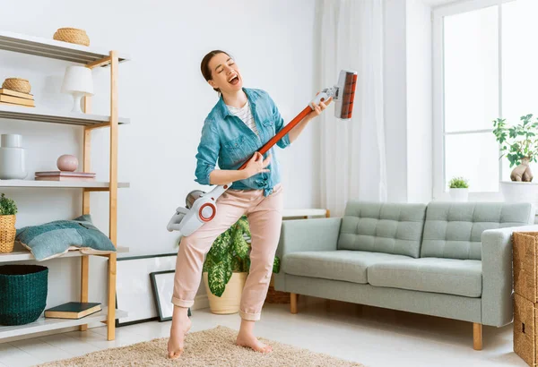 Happy woman vacuuming the room. Housewife doing the cleaning in the house.