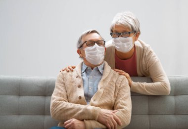 Coronavirus ve grip salgını sırasında maske takan yaşlı bir çift. Virüs ve hastalık koruması, ev karantinası. COVID-2019. Maskeleri çıkarmak ya da çıkarmak.