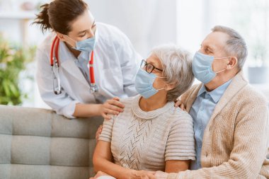 Doktor ve yaşlı çift koronavirüs ve grip salgını sırasında maske takıyor. Virüs koruması, ev karantinası. COVID-2019. Maske takıyor.