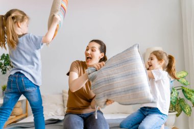 Sevgi dolu bir aile! Anne ve çocukları evde yastıklarda kavga ediyorlar..