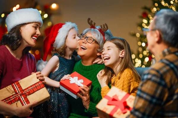 メリークリスマスとハッピーホリデー おばあちゃん おじいちゃん お母さん 子供たちが贈り物を交換します 屋内で木の近くで遊んでいる両親と娘 プレゼント付きの家族を愛する — ストック写真