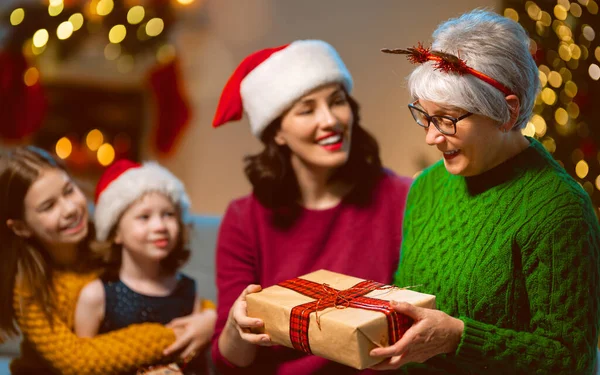 圣诞快乐 节日快乐 快乐的孩子们送给妈妈和奶奶礼物 父母和小孩在室内的树上玩得很开心 有礼物在房间里的爱的家庭 — 图库照片