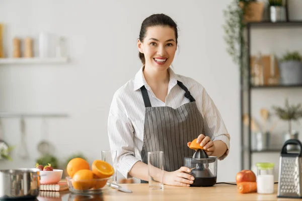 健康的食物在家里 快乐的女人正在厨房里准备新鲜的橙汁 — 图库照片