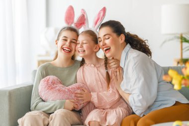 İyi tatiller. Anne ve kızları. Paskalyayı kutlayan aile. Sevimli küçük çocuklar tavşan kulağı takıyor.. 