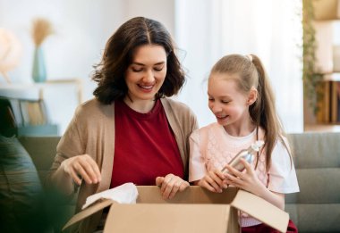 Anne ve kızı karton kutuları boşaltıyorlar. Çevrimiçi alışveriş kavramı.