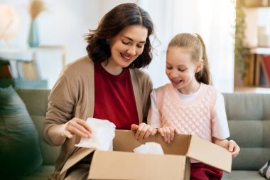 Anne ve kızı karton kutuları boşaltıyorlar. Çevrimiçi alışveriş kavramı.