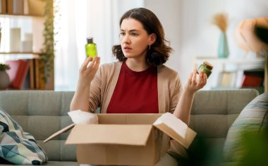Kadın karton kutuları açıyor. Hayal kırıklığına uğramış online alışveriş kavramı.