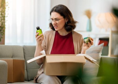 Kadın karton kutuları açıyor. Hayal kırıklığına uğramış online alışveriş kavramı.