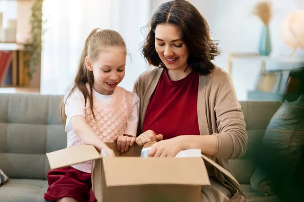 Anne ve kızı karton kutuları boşaltıyorlar. Çevrimiçi alışveriş kavramı.
