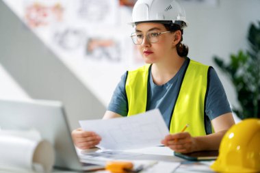 Kadın mimar inşaat alanında planlar üzerinde çalışıyor..