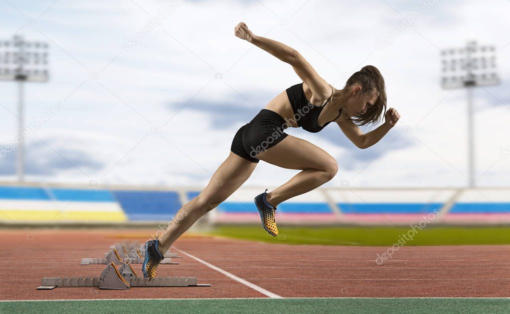 Woman sprinter leaving starting blocks on the athletic track. Exploding start