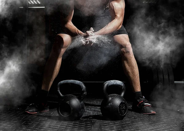 Weightlifter clapping hands and preparing for workout at a gym. Focus on dust