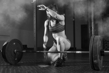 Kadın el çırpıyor ve spor salonunda antrenmana hazırlanıyor.