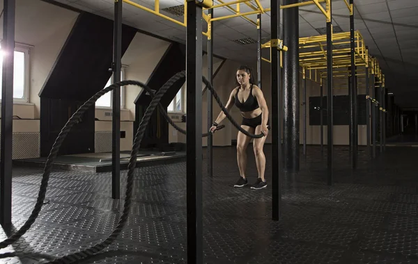 Woman working out with battle ropes at gym