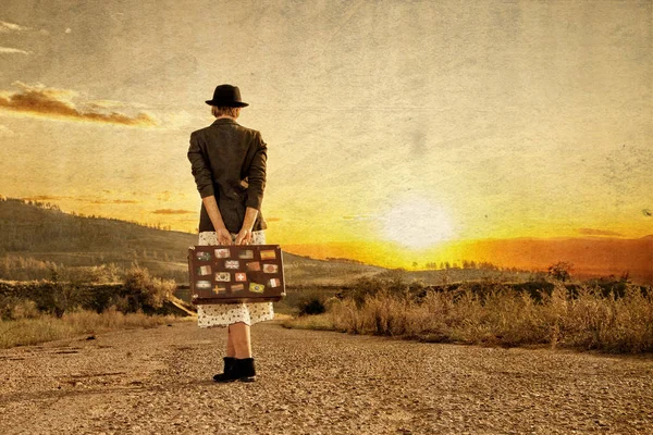 Women with vintage travel suitcase at old road. Photo in old image style