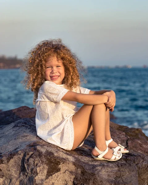 海の近くの岩に白いドレスの少女 — ストック写真