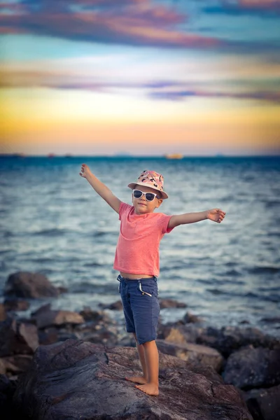 海の近くの岩の上の上げられた手の小さな男の子 — ストック写真