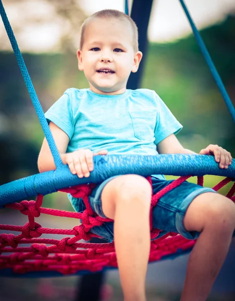 Kleine jongen swingend op een schommel — Stockfoto
