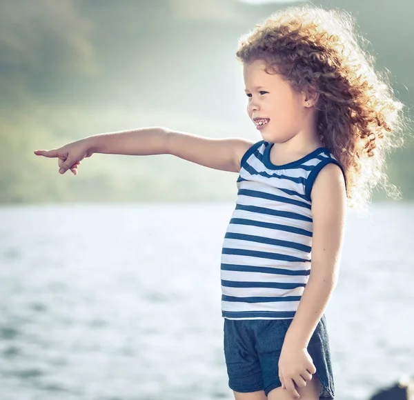 Маленькая девочка указывает на море — стоковое фото