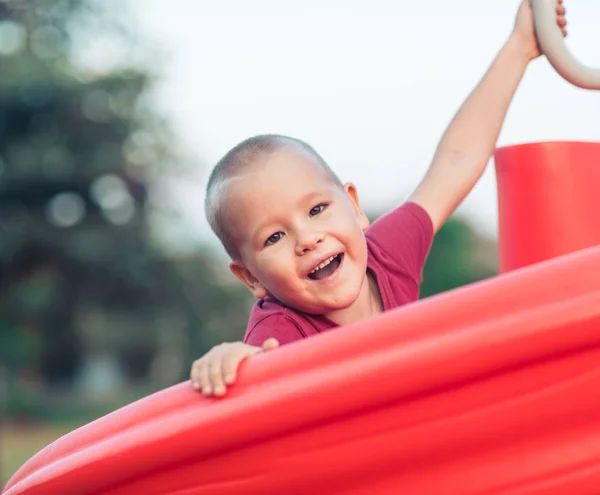 Piccolo ragazzo sorridente su uno scivolo — Foto Stock