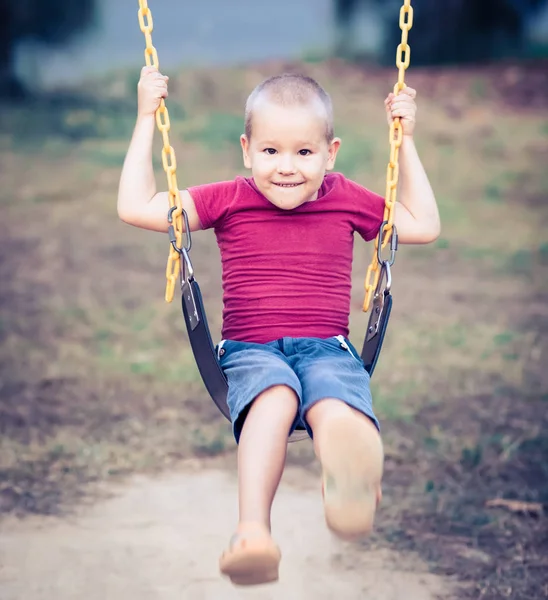 Menino balançando em um balanço — Fotografia de Stock